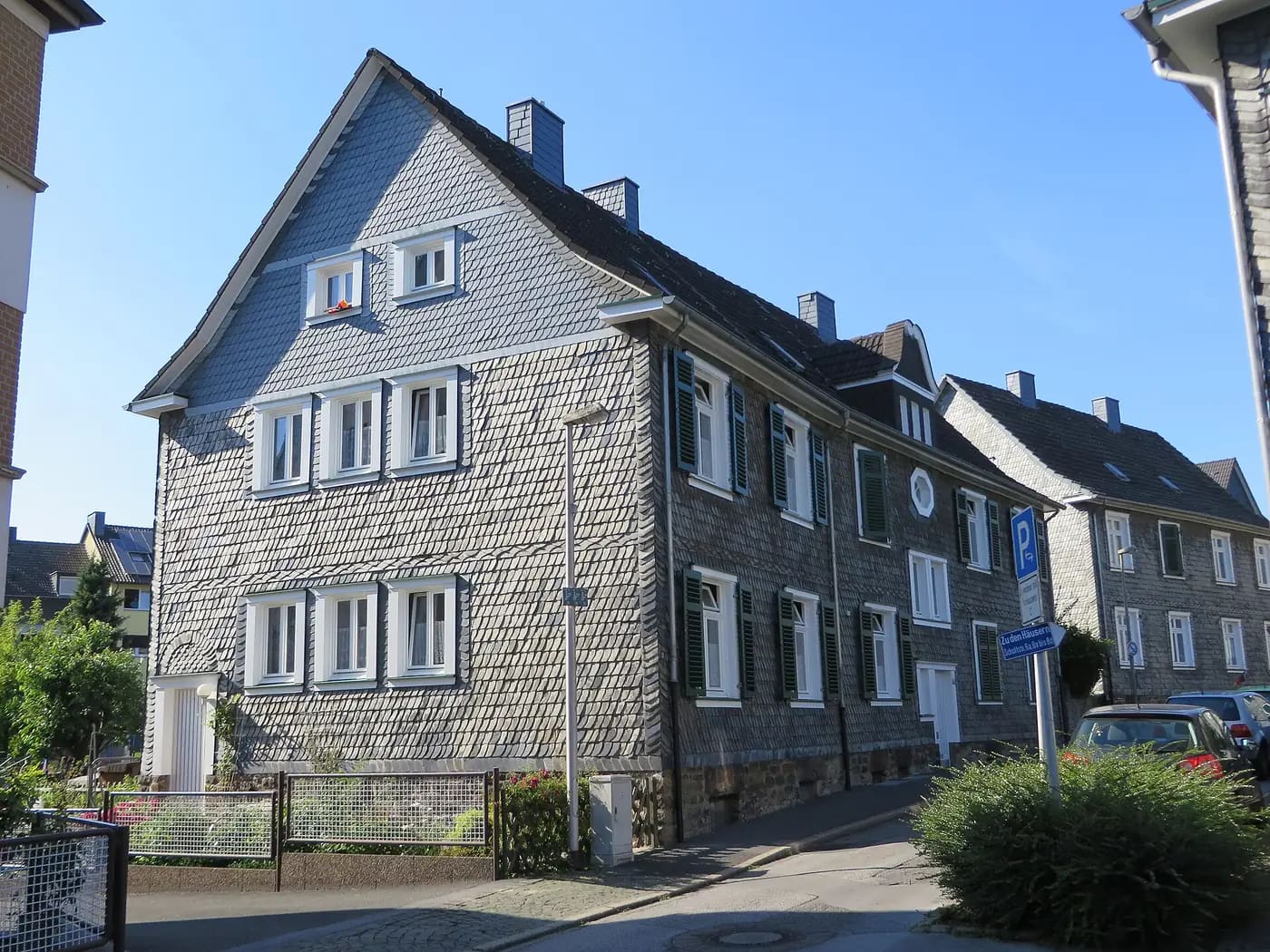 Schiefergedeckte Wohnhäuser der Gartenstadt Crengeldanz an der Schottstraße, mit grünen Fensterläden und kleinen Vorgärten