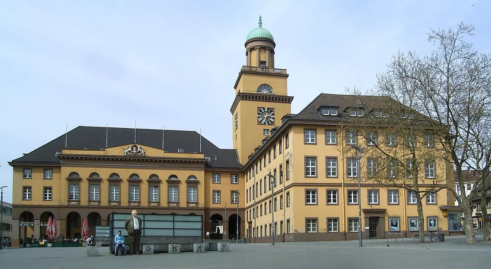 Das gelbe Rathaus von Witten mit Uhrturm und grüner Kuppel, davor der weite gepflasterte Rathausplatz