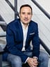 Christian Gottschling sitzt im blauen Sakko über Jeans auf einer Metalltreppe
