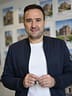 Christian Gottschling hält einen Wohnungsschlüssel in der Hand, dahinter eine Wand mit Objektunterlagen